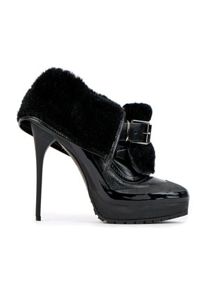 Chaussure noire à talon haut avec plateforme, finition brillante, sangle épaisse avec boucle et revêtement doux et duveteux sur la partie supérieure.