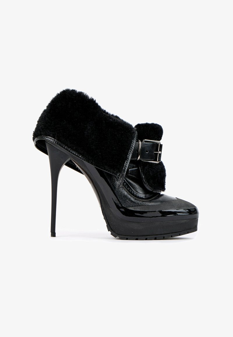 Chaussure noire à talon haut avec plateforme, finition brillante, sangle épaisse avec boucle et revêtement doux et duveteux sur la partie supérieure.
