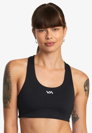 Sujetador deportivo negro hecho de material elástico. Presenta un escote en forma de scoop y un logo blanco en el centro. Textura suave, diseñado para la comodidad.