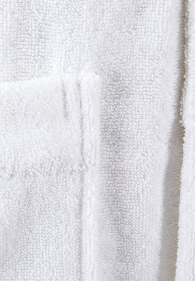 Peignoir en éponge blanche avec une surface douce et texturée. Il possède une poche à rabat et un design droit. Matériau léger et absorbant.