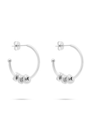 Par sølv hoops øreringe med tre snoede metalringe på hver, med butterfly-lukninger på en hvid baggrund.