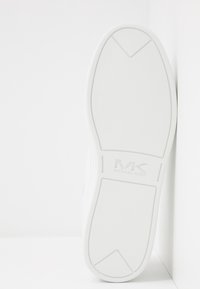 Suela de zapatilla de goma blanca con superficie texturizada. Presenta el logo "MK" en relieve. Bordes suaves y diseño minimalista.