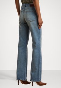 Šviesiai mėlynos tiesios kojos džinsai, pagaminti iš džinsinio audinio, turintys vidutinio aukščio liemenį, dvi užpakalines kišenes ir lygų, šiek tiek išblukusį paviršių.