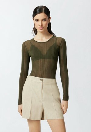 Bodysuit à manches longues côtelé vert olive avec un design translucide, doté d'un col rond, associé à un short beige ajusté avec un bouton.