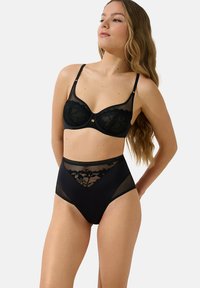 Set de lingerie noir comprenant un soutien-gorge en dentelle avec des panneaux en maille et un slip taille haute avec des détails en dentelle florale. Tissu lisse, forme structurée.