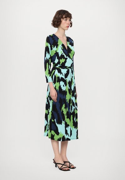 Rochie lungă tip wrap, cu un model abstract în nuanțe de albastru, verde și negru. Decolteu în V, mâneci lungi și talie legată. Asortată cu sanda cu toc negru.