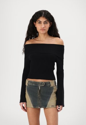 Black off-the-shoulder ribbed crop top paired with a patchwork denim mini skirt featuring side panels and a front zipper.