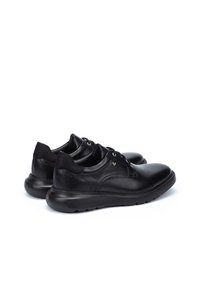 Zapatos de cuero negro con textura suave, punta redondeada y detalles de cordones. Cuentan con una suela de goma acolchada y un sutil logotipo en el lateral.