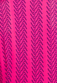 Lyserødt stof med et gentaget chevron-mønster i mørkeblå. Designet har skarpe, zigzaglinjer med en glat tekstur.