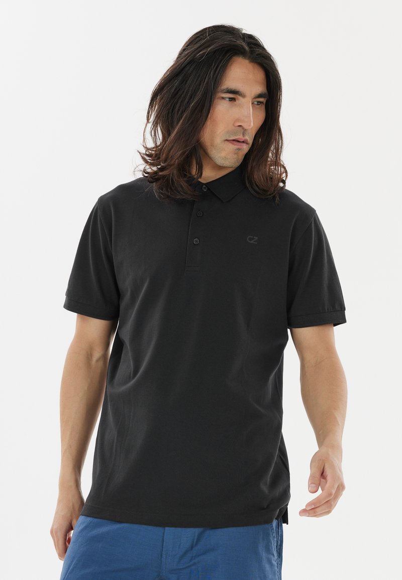 Sort polo shirt fremstillet af bomuld med klassisk krave, placket med tre knapper og korte ærmer. Har et diskret logo på venstre bryst.
