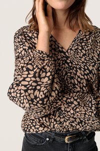 Sort bluse med beige abstrakt mønster, med V-udskæring, samlede ærmer og knapper foran. Kombination med mørke jeans og et sort bælte.
