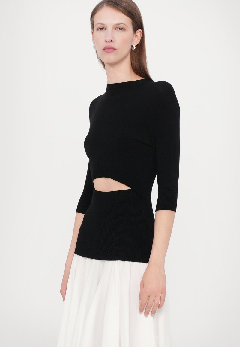 Schwarzes gestricktes Oberteil mit kurzen Ärmeln, das einen markanten Ausschnitt an der Taille aufweist. Glatte Textur, taillierter Schnitt und Rundhalsausschnitt.