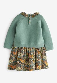 Pletený tyrkysový top s květinovou sukni. Rukáv s volánky a třemi knoflíky. Měkká textura a pohodlný střih.