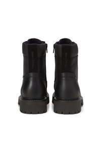 Schwarze Leder-Stiefeletten mit strukturiertem Oberflächenmaterial, ausgestattet mit seitlichen Reißverschlüssen, elastischen Einsätzen und robusten Sohlen für besseren Halt.