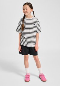 Vit och marinblå randig t-shirt, svarta shorts, rosa sneakers med kardborreband och vita strumpor. Avslappnad outfit lämplig för barn.