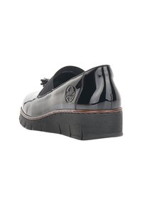 Chaussure à enfiler en cuir verni noir avec détail à pampilles, semelle épaisse texturée et logo de la marque sur le talon latéral.