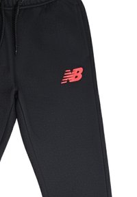 Pantaloni jogging neri con vita elasticizzata, dotati di un logo rosso New Balance sulla coscia sinistra e una texture in tessuto sintetico liscia.
