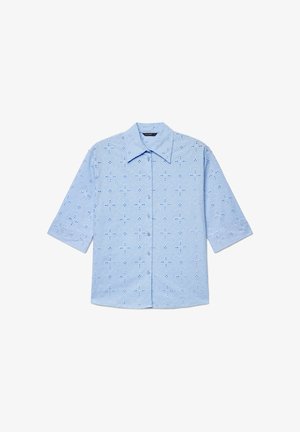 Hellblaues Kurzarmhemd mit Knöpfen, floraler Lochstickerei und spitzem Kragen, ordentlich flach auf einem weißen Hintergrund ausgelegt.