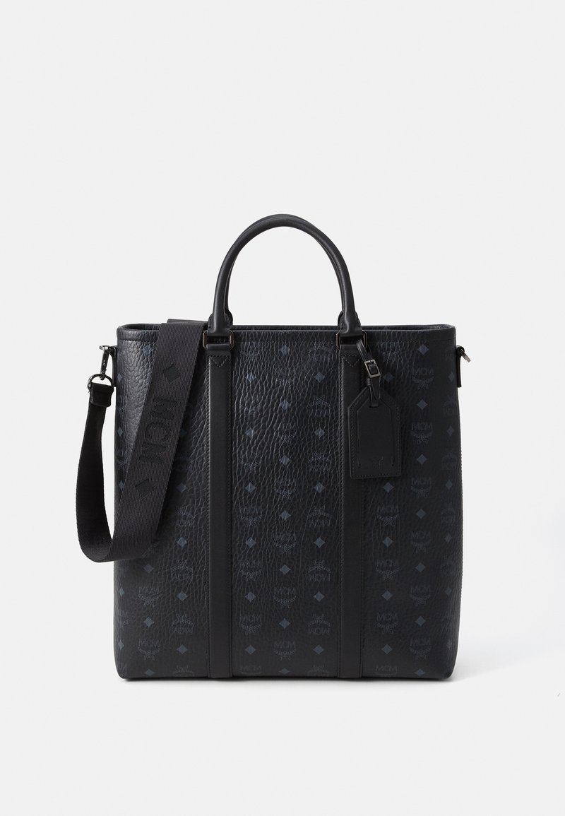 Sac fourre-tout en cuir noir avec finition texturée, arborant un motif de logo répétitif, des poignées doubles, une bandoulière amovible et une étiquette.