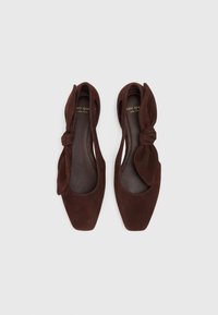 Brown suede flats with a square toe and a knotted bow accent on each side. Smooth inner lining and flat sole.