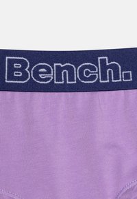Lila Stoffbrief mit einem marineblauen elastischen Bund, der das weiße "Bench."-Logo trägt. Weicher Stoff, nahtloses Design und enganliegender Schnitt.