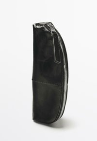 Sort læderpung med en blank finish, buet form, sølvlynlås og en tekstureret overflade med synligt sømdetalje.