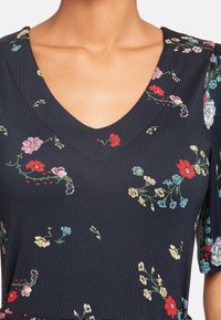 Marinblå blommig klänning med V-ringning, korta ärmar och olika färgglada blommönster på en texturerad tyg.