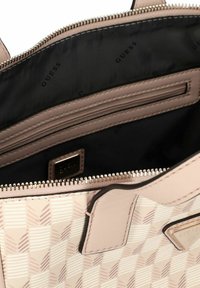 Sac à main rose à motif avec une texture lisse, doté d'une fermeture zippée et d'une doublure intérieure noire avec un logo en relief.
