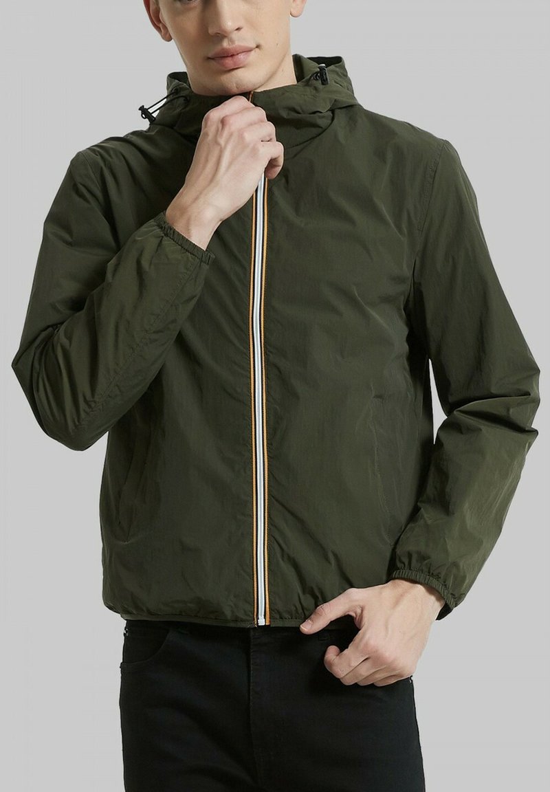 Veste légère vert olive avec capuche, dotée d'une fermeture éclair avant avec des rayures multicolores et de poignets élastiques pour un ajustement sécurisé.