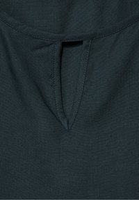 Ciemnozielona tkanina o gładkiej fakturze, z dekoltem w kształcie litery V i delikatnymi przeszyciami. Brak wzorów i zdobień.