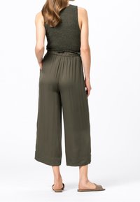 Zielonooliwkowy, prążkowany top na ramiączkach w zestawie z luźnymi, wysokim stanem spodniami o długości 3/4. Miękka tkanina, luźny fason, z płaskim pasem i bocznymi rozcięciami.