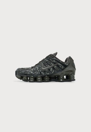 Must Nike jooksujalanõu, millel on jaotatud tallapadi ning valge täpikujuline muster ülaosa kangal, nähtav välisküljelt.
