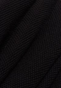 Tessuto a maglia nero con un motivo testurizzato, caratterizzato da una finitura liscia e una leggera lucentezza, che mostra cuciture intricate e pieghe.
