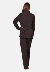 Brown fleece lounge set featuring a long-sleeve top with a collared neckline and relaxed fit pants with a straight cut. Soft texture.