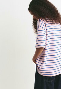 Csíkos t-shirt rózsaszínben, kék vízszintes csíkokkal, rövid ujjaival és laza fazonban, puha pamut anyagból készült.