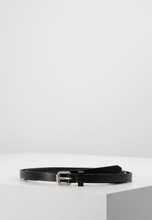 Black leather belt with a silver rectangular buckle, laid coiled on a white surface against a plain light gray background.