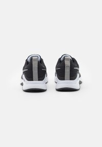 Scarpe sportive nere realizzate in rete traspirante, con un tallone grigio e suola bianca. Design semplice con un branding discreto sul retro.