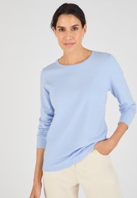 Lichtblauwe, lange mouwen trui met een ronde hals, zachte textuur en een relaxed fit, gecombineerd met lichtbeige broeken.