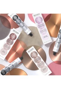 Tubes de Revlon Nutri Color dans un emballage gris et rose sur des fonds métalliques circulaires. Surfaces texturées dans des tons dorés, rose et cuivre.