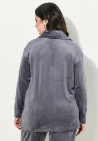 Giacca in pile grigia con colletto ripiegabile, maniche lunghe e vestibilità ampia. Tessuto morbido senza motivi visibili o parti metalliche.