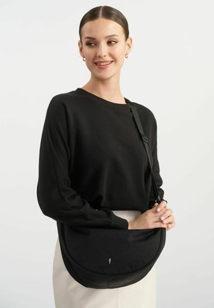 Czarna torebka na ramię o eleganckim, wygiętym kształcie i gładkiej teksturze. Posiada regulowany pasek oraz subtelne logo z przodu.