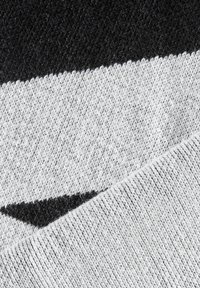 Țesătură tricotată cu dungi negre și gri, având o textură moale. Designul include modele diagonale și un finisaj curat, țesut.