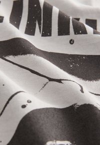 Tessuto di cotone con una texture ondulata presenta un design grafico in bianco e nero, comprendente forme astratte e motivi a schizzi.