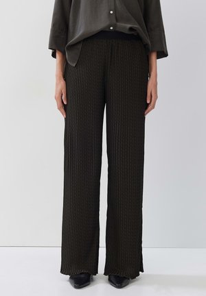 Dark green, textured, wide-leg trousers with a ribbed pattern and elastic waistband, paired with a loose, button-up shirt.