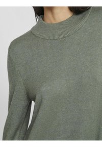 Green sweater featuring a ribbed high neckline, soft texture, and long sleeves, shown from the chest up against a neutral background.
