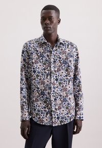 Camicia con bottoni a fiori caratterizzata da un motivo blu, bianco e marrone su un tessuto leggero, dotata di colletto classico e maniche lunghe.