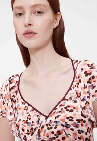 Gėlėtu raštu suknelė iš minkštos medžiagos, su V formos iškirpte ir raukinėtais rankovėliais. Spalvų paletėje dominuoja rožinė, oranžinė ir subtilios mėlynos spalvos akcentai.