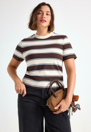 Bruine en crèmekleurige gestreepte t-shirt met een ronde hals en korte mouwen. Gecombineerd met donkere jeans en een bruine handtas met accenten en charm-details.