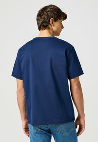 Maglietta blu navy in cotone, con scollo rotondo, maniche corte e vestibilità comoda, vista da dietro.