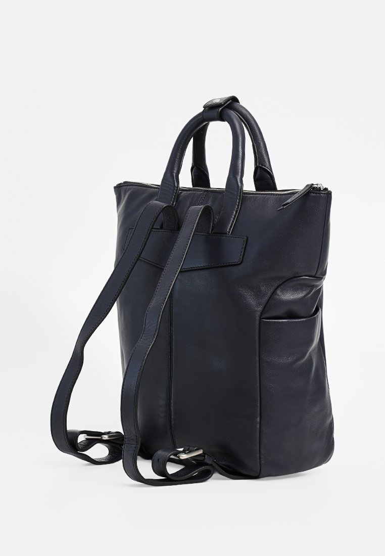 Granatowy skórzany plecak z podwójnymi uchwytami u góry i regulowanymi paskami, z zamknięciem na zamek błyskawiczny oraz boczną kieszenią dla dodatkowego przechowywania.